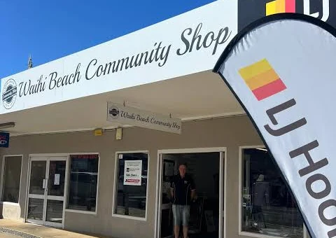 The Waihi Beach Community Shop shopfront on Wilson Road, with its white sign and LJ Hooker next door